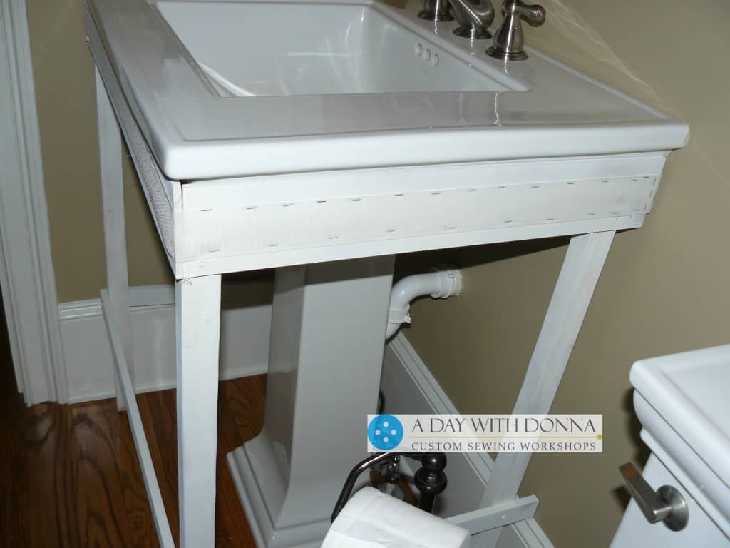 You will want the back legs of your pedestal sink framework to clear any floor molding. The legs are not flush with the wall, but flush with the floor mold.