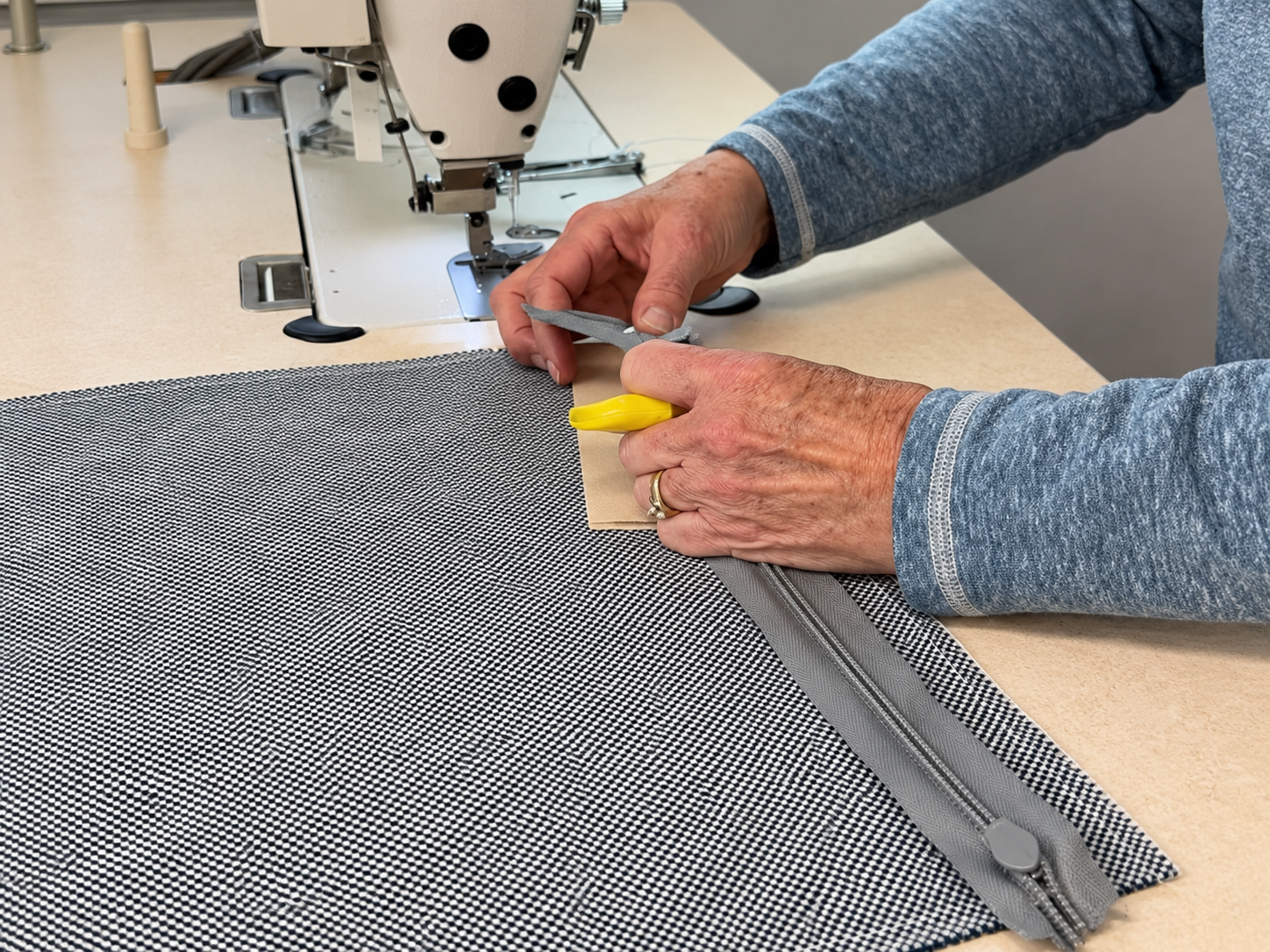Hands installing a zipper on solid colored fabric Hands installing a zipper on solid colored fabric